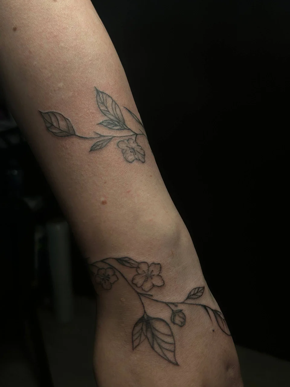 Smalki ziedu un lapu tetovējumi uz rokas